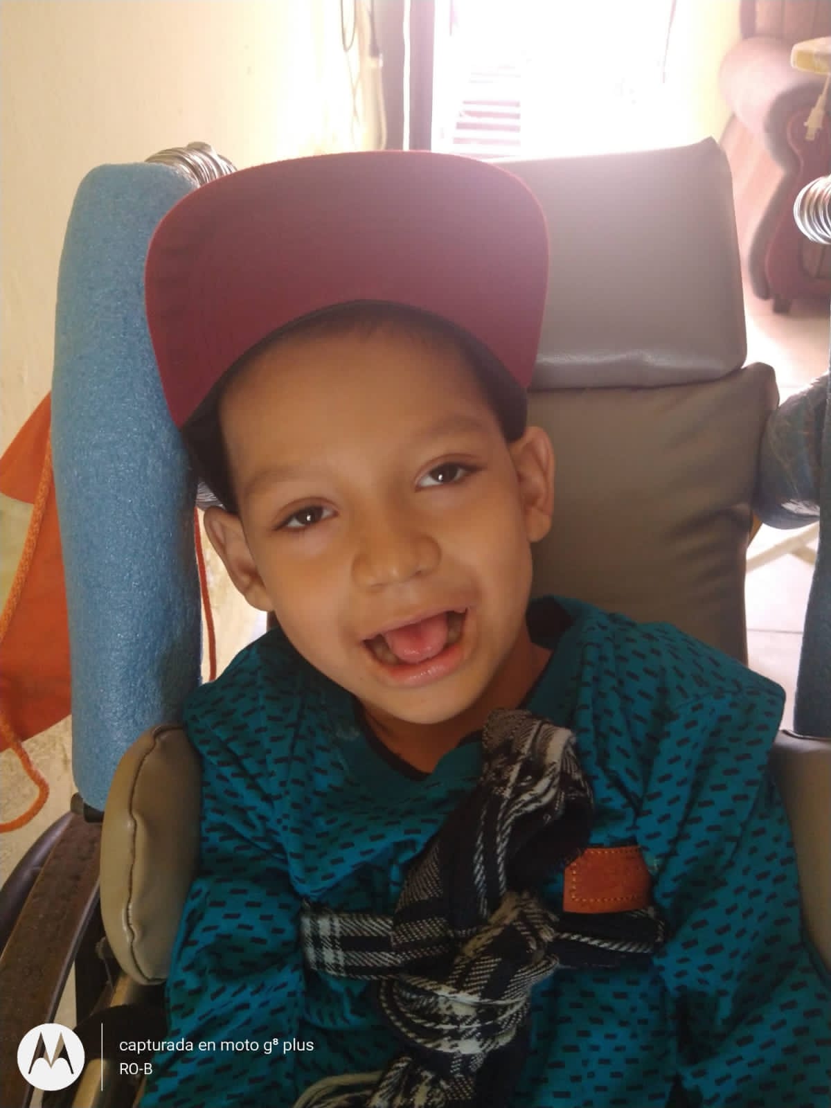 Niño de la comunidad sonriendo en su silla de ruedas
